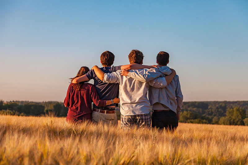 Vier Junge menschen in einem Getreidefeld arm in Arm
